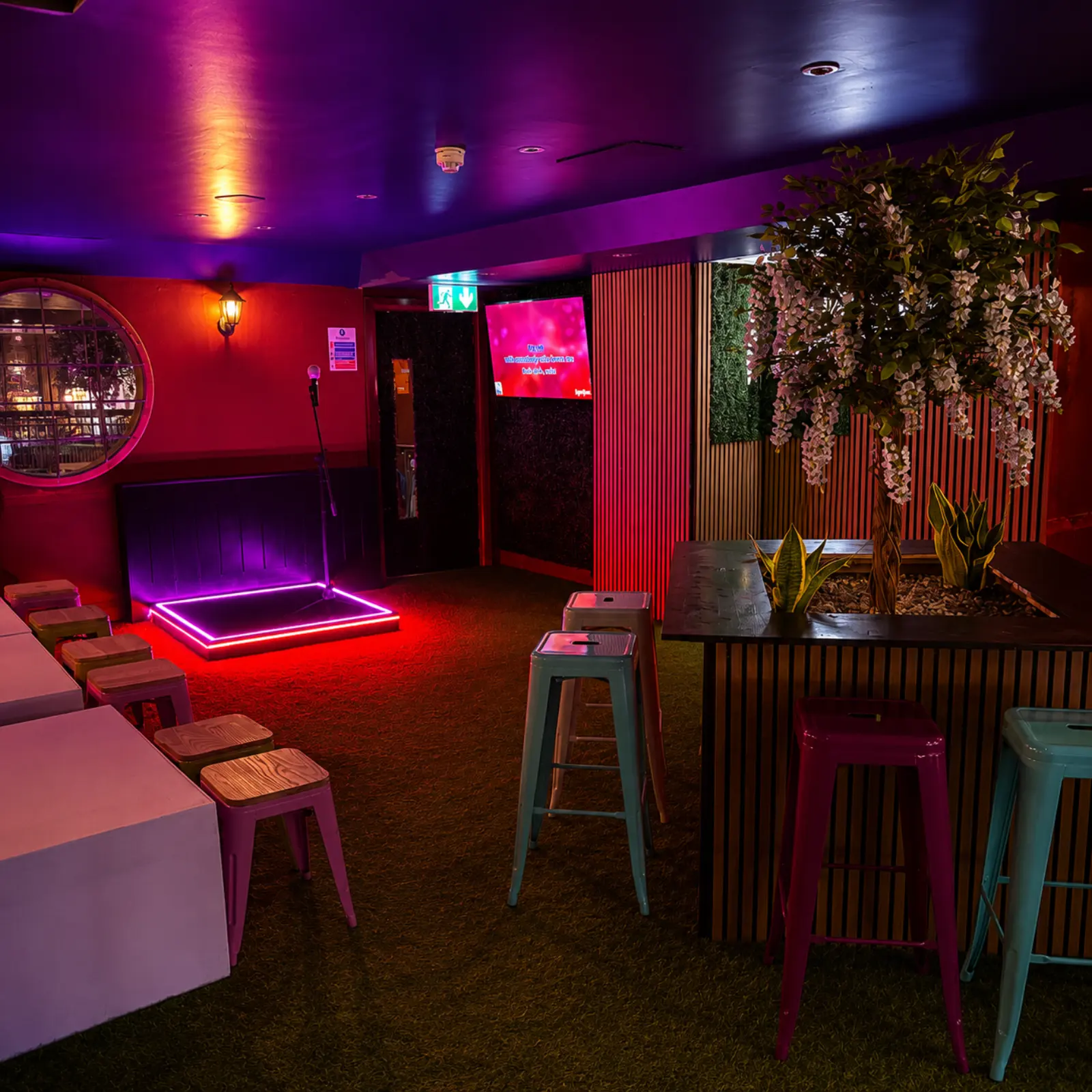 Neon karaoke stage and microphone beside high tables at Plunkets karaoke bar in Dublin 1