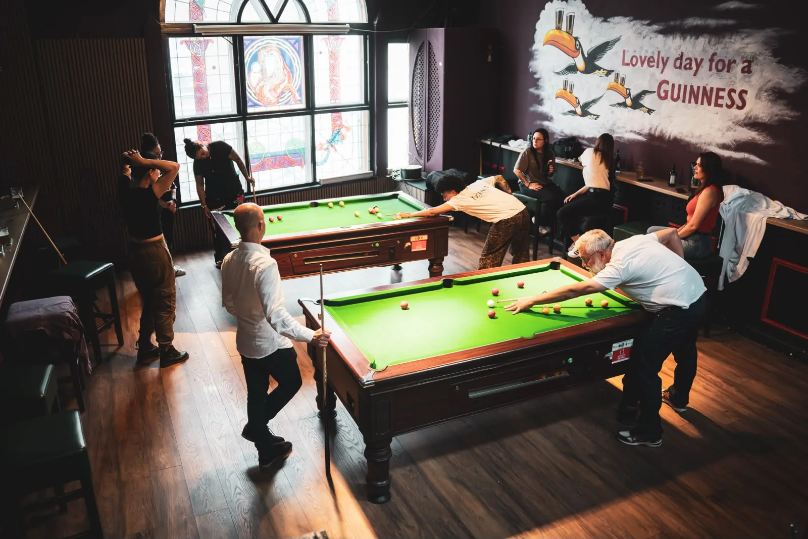 Friends playing pool at Plunkets Pub Dublin city centre next to the Guinness mural